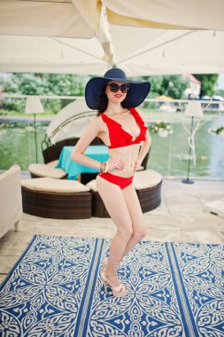 Korku veren genç kadın kırmızı bikini şapka ve güneş gözlüğü ile poz