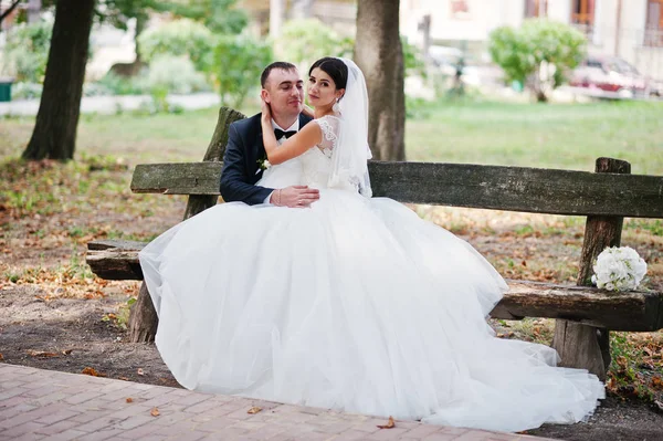 Fantastic wedding couple sitting on the bench in the park on the — Stock Photo, Image