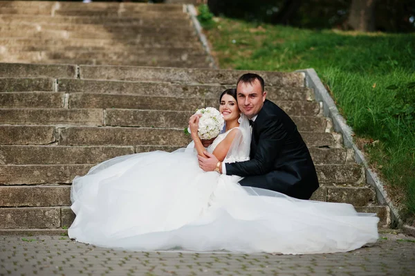 Casal de casamento perfeito posando nas escadas no parque . — Fotografia de Stock