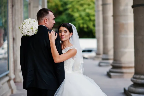 Fabulous wedding couple walking and posing next to the columns o — Stock Photo, Image