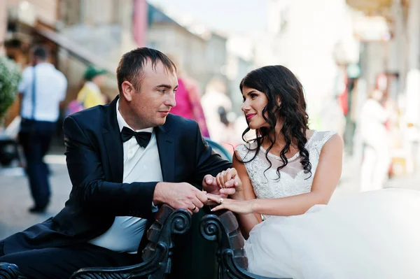 Lindo casamento casal sentado no banco no centro de th — Fotografia de Stock