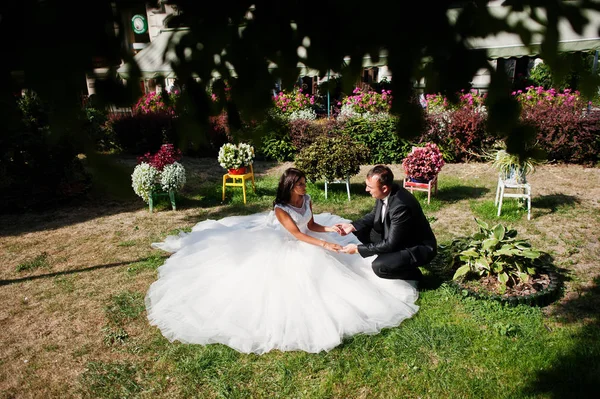 Fantastic wedding couple sitting on the grass in a stunning gard — Stock Photo, Image