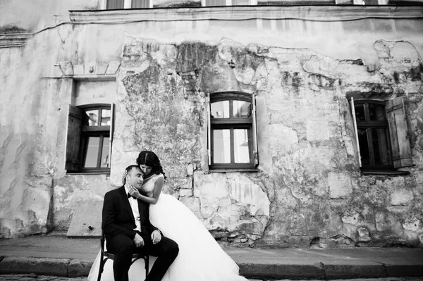 Handsome groom sitting on the chair with a beautiful bride stand — Stock Photo, Image