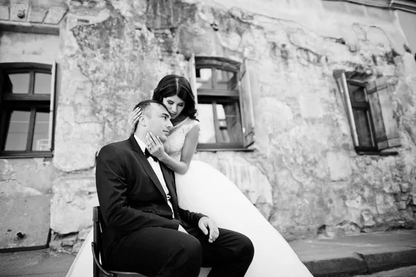 Handsome groom sitting on the chair with a beautiful bride stand — Stock Photo, Image