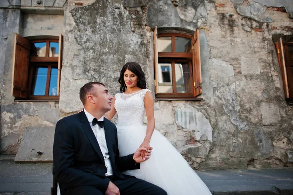 Güzel gelin stand ile sandalye üzerinde oturan yakışıklı damat