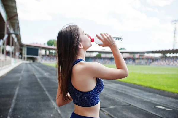 Retrato de una mujer en forma bebiendo agua después de correr en el stad — Foto de Stock