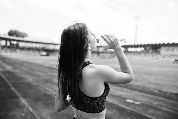 Портрет здоровой женщины, пьющей воду после бега по стадиону — стоковое фото