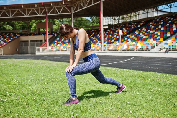 Retrato de uma mulher bonita em sportswear esticando seu muscl — Fotografia de Stock