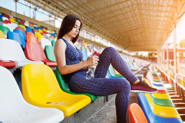 Retrato de uma mulher bonita em sportswear sentado e bebendo wa — Fotografia de Stock