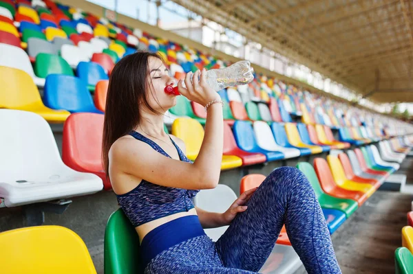 Retrato de uma mulher bonita em sportswear sentado e bebendo wa — Fotografia de Stock