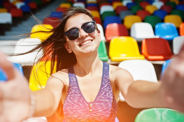 Yakın çekim portre bir güzel kız oturan güneş gözlüğü içinde uygun. 