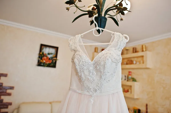 シャンデリア上のラックに掛かっている素敵な白いウェディング ドレス — ストック写真