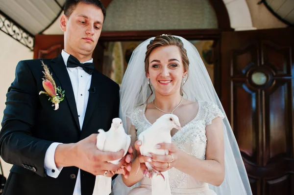 Casal de casamento impressionante liberando pombas para o céu . — Fotografia de Stock