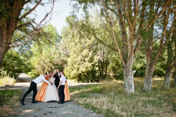 Gyönyörű esküvői pár gyaloglás és birtoklás móka-val a koszorúslányok és a groomsmen a parkban. — Stock Fotó