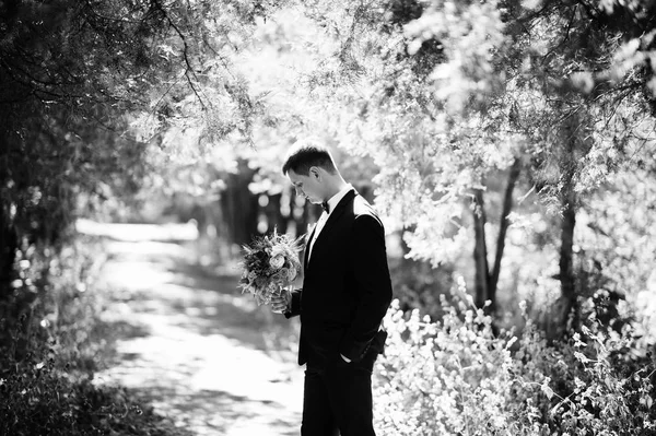 Retrato de um belo noivo segurando o passeio buquê de sua esposa em — Fotografia de Stock