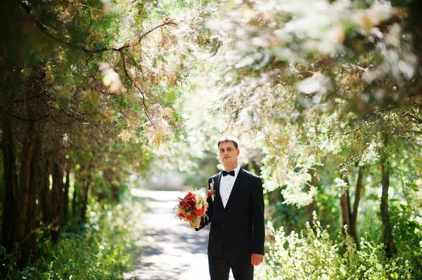 Ritratto di un bellissimo sposo che tiene il bouquet di sua moglie entrare — Foto Stock