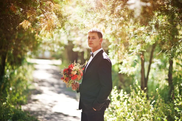 Retrato de un novio guapo sosteniendo el ramo de su esposa —  Fotos de Stock