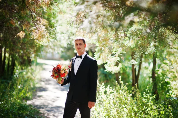 Portrait d'un beau marié tenant le bouquet de sa femme — Photo
