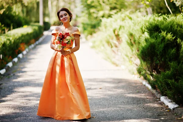 Vonzó koszorúslány narancssárga ruhában pózol a menyasszonyi csokor — Stock Fotó