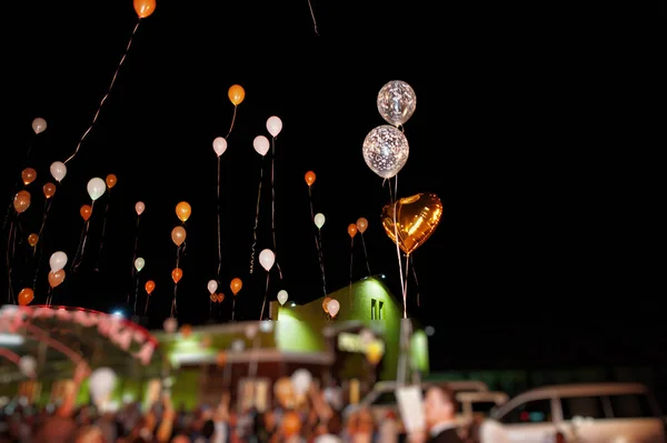 Guests with bride and groom releasing ballons in the air at wedd — Stock Photo, Image