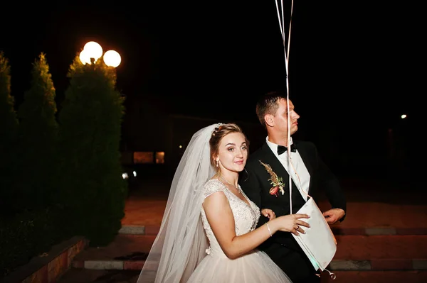 Casal de casamento fantástico; perder com balões à noite ao ar livre . — Fotografia de Stock