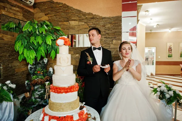 Gorgeous wedding couple cutting their cake with knife in restaur — Stock Photo, Image