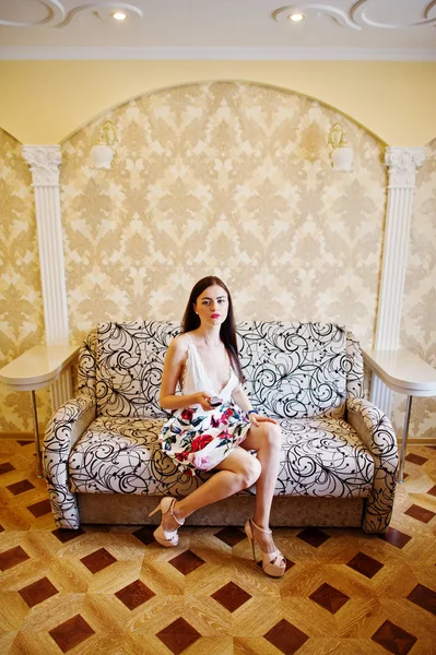 Portrait d'une belle fille en robe florale assise sur le canapé — Photo