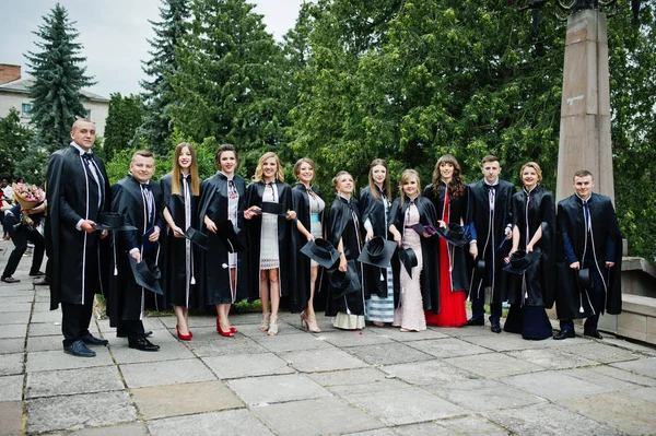 Τεράστια ομάδα των αποφοίτων στα Φορέματα Αποφοίτησης και καπάκια που παρουσιάζουν εξωτερι — Φωτογραφία Αρχείου