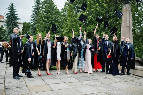 Happy university graduates throwing their graduation caps into t