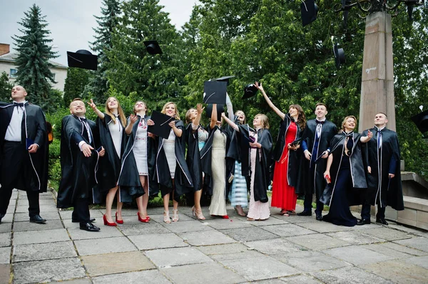 Happy university graduates throwing their graduation caps into t