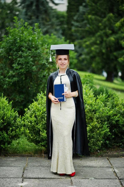 Portrait of a beautiful female graduate in dress and graduation