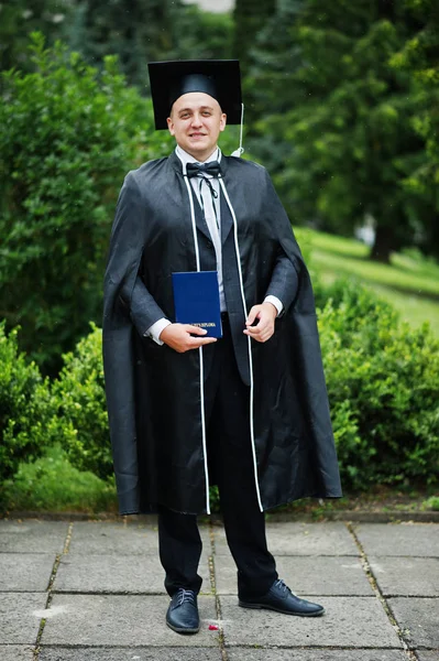 Portrait of an elegant young man in park dressed in graduation g — Stock Photo, Image