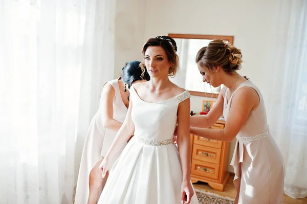 Подружки нареченої допомагають прекрасній нареченій одягатися і готуватися до — стокове фото
