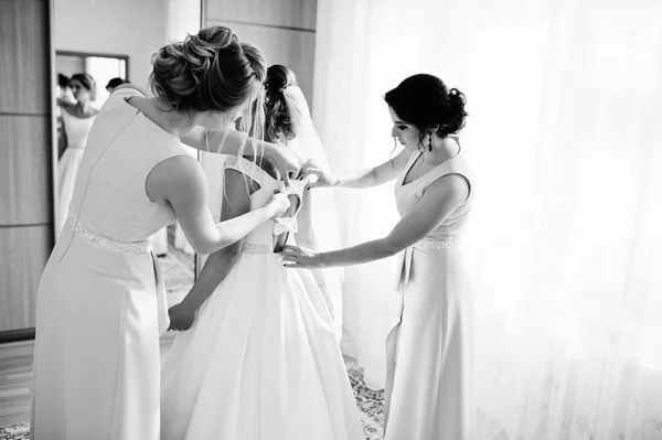 Damas de honor ayudando a novia hermosa a vestirse y prepararse para — Foto de Stock