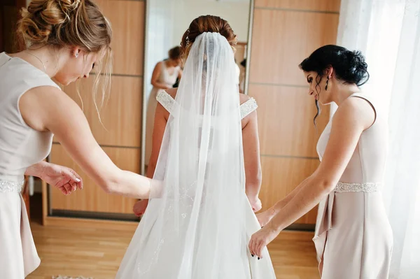 Bridesmaids helping gorgeous bride to dress up and get ready for — Stock Photo, Image