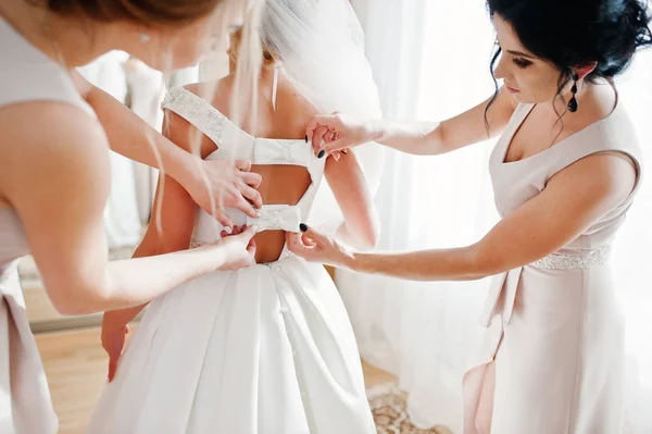 Damas de honor ayudando a novia hermosa a vestirse y prepararse para — Foto de Stock