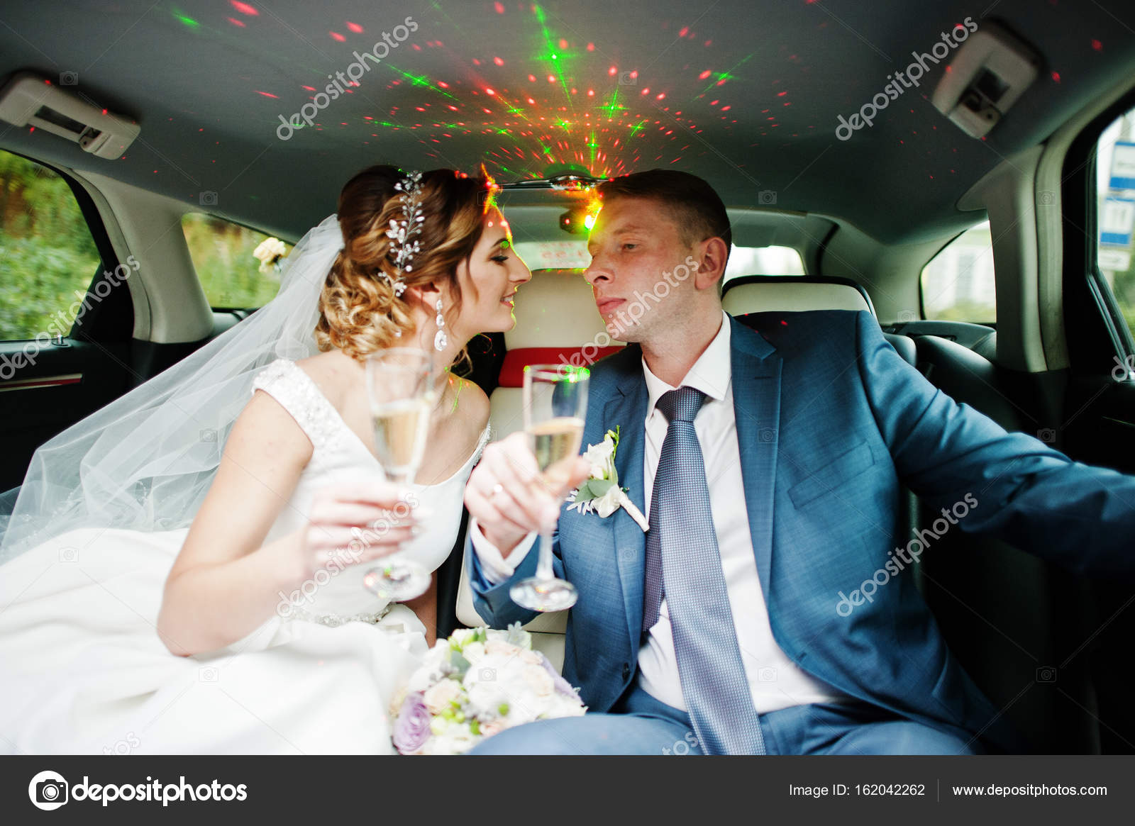 Newly married couple drinking champagne in the limousine on thei