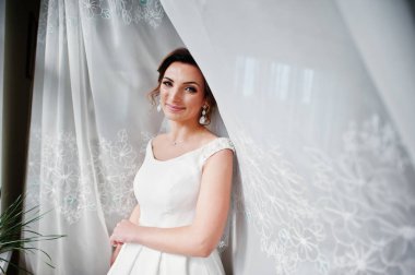 Arkadaki perdeler ile poz çekici bir gelin portresi