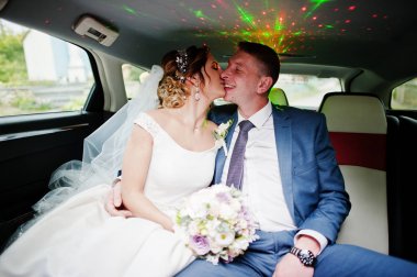 Harika düğün çift oturma ve limuzin içinde öpüşme.