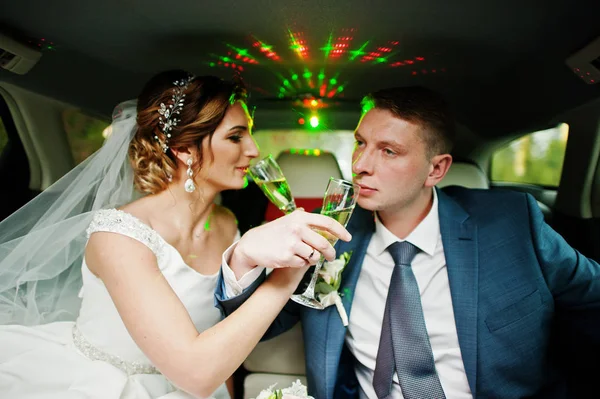 Pareja recién casada bebiendo champán en la limusina en su — Foto de Stock