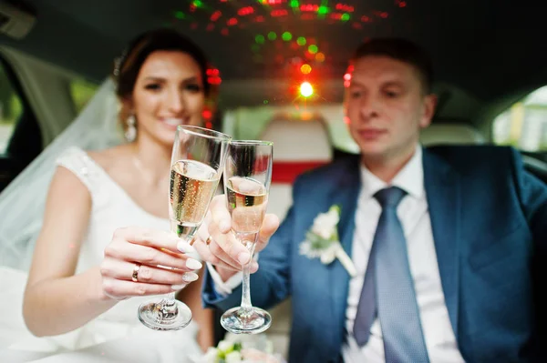 Újonnan házas pár pezsgőt isznak a thei limuzinban — Stock Fotó