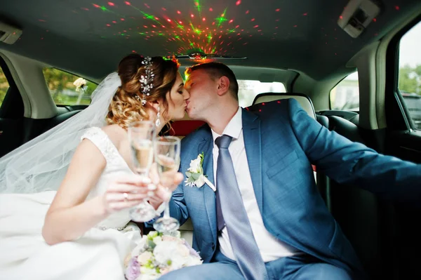 Una coppia appena sposata che beve champagne in limousine — Foto Stock