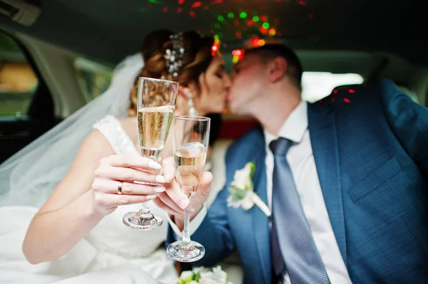 Newly married couple drinking champagne in the limousine on thei — Stock Photo, Image