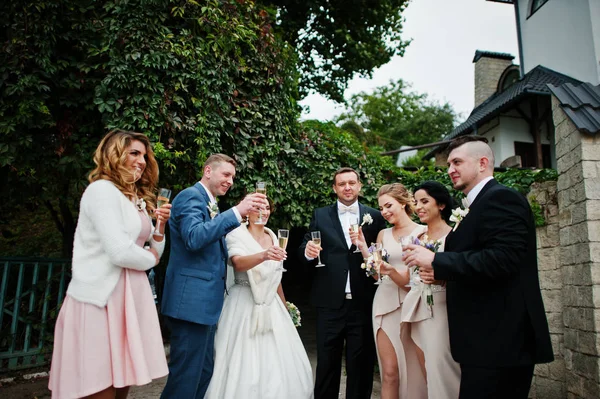 Pareja de bodas, damas de honor y padrinos bebiendo champán — Foto de Stock