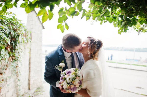 Awesome wedding couple walking and kissing in the park with lake — Stock Photo, Image