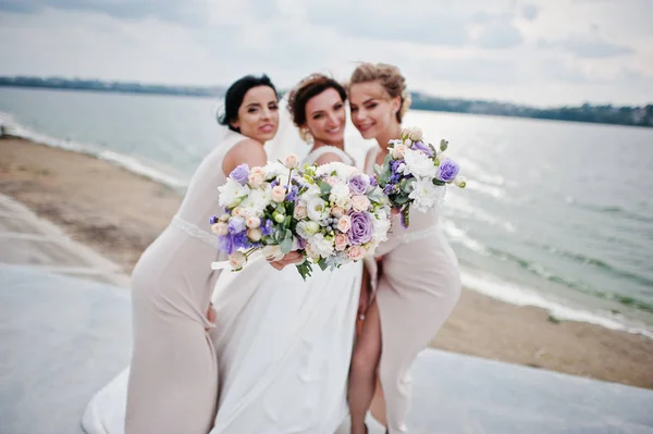 Splendida sposa con belle damigelle in posa con mazzi di fiori su t — Foto Stock