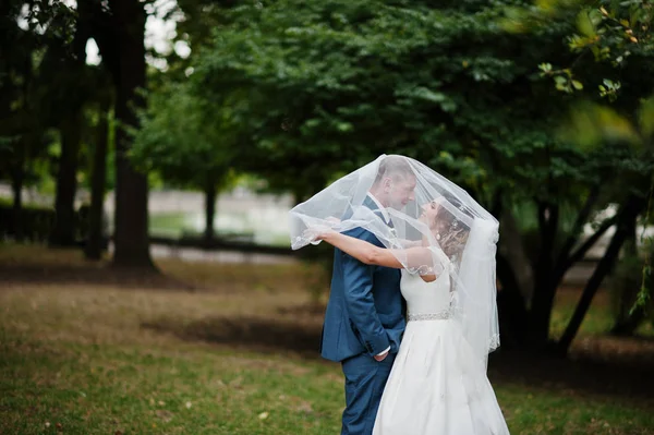Matrimonio coppia posa sotto il velo nuziale all'aperto . — Foto Stock