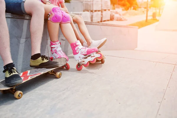 Foto de cerca de las piernas masculinas en el monopatín y las piernas femeninas en rol — Foto de Stock