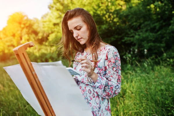 Portrait of an attractive young woman in long dress painting wit — Stock Photo, Image