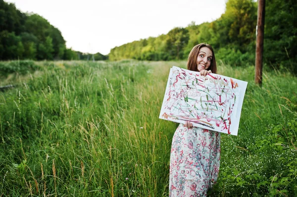 Retrato de uma bela jovem mulher artsit segurando sua pintura em — Fotografia de Stock